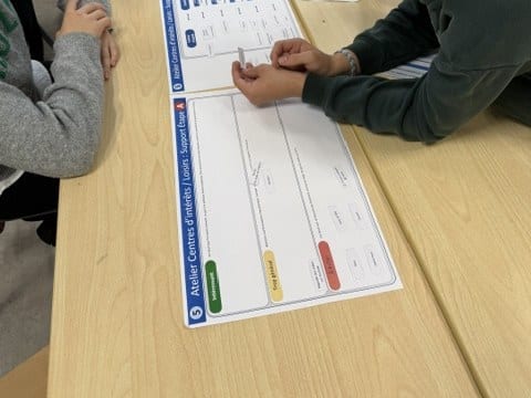 Un élève place une étiquette sur le plateau « Centres d’intérêt / Loisirs »